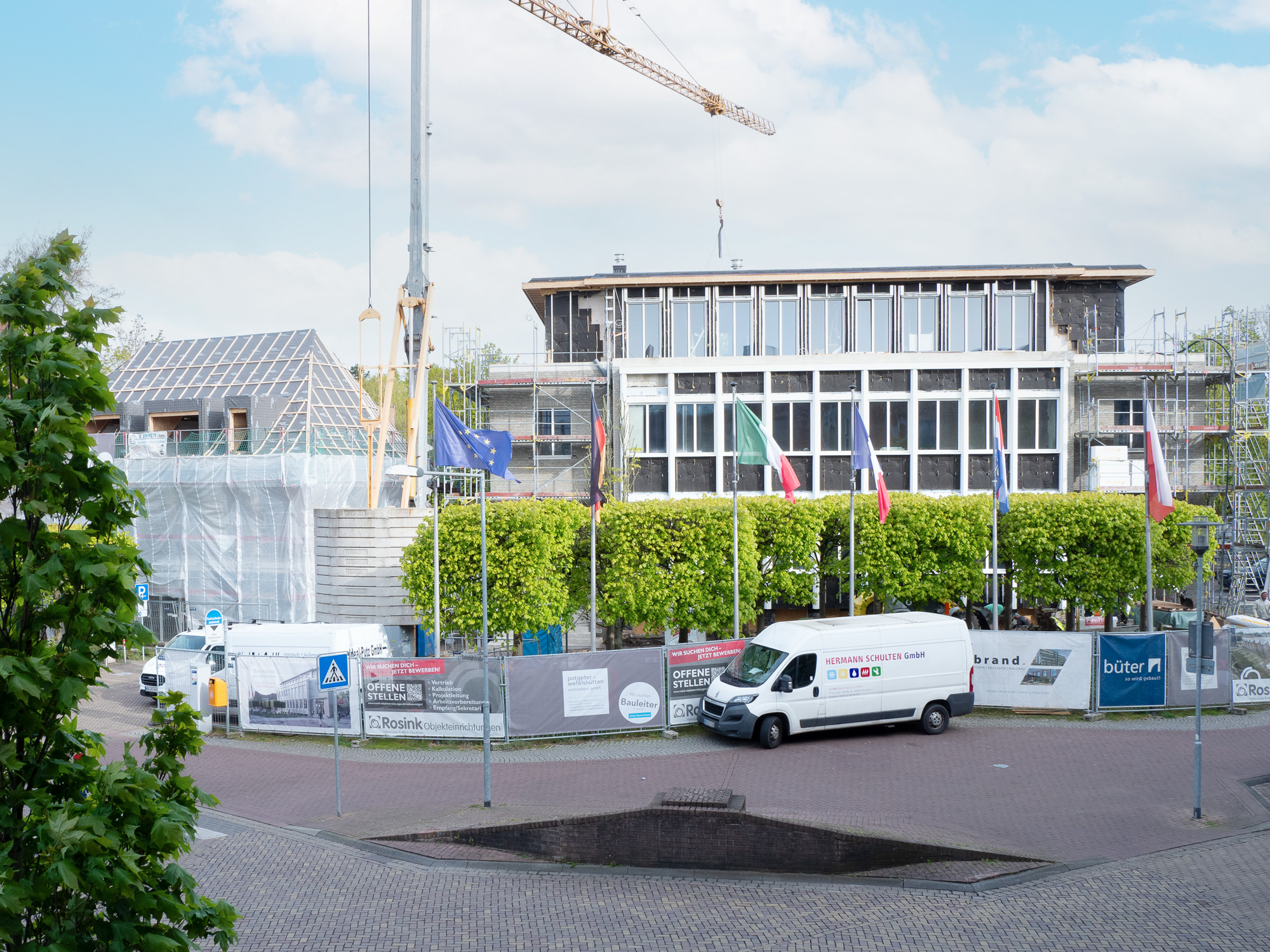 Bauarbeiten am Europaplatz im Mai 2024: Umbau des ehemaligen Gebäudes der Deutschen Bank zu einem modernen Wohn- und Bürogebäude. Ein Transporter der Hermann Schulten GmbH parkt vor der Baustelle.